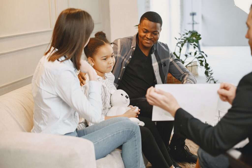 familia de tres sentada en sofa frente a terapeuta en terapia familiar
