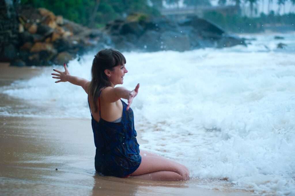 chica frente al mar con los brazos abiertos