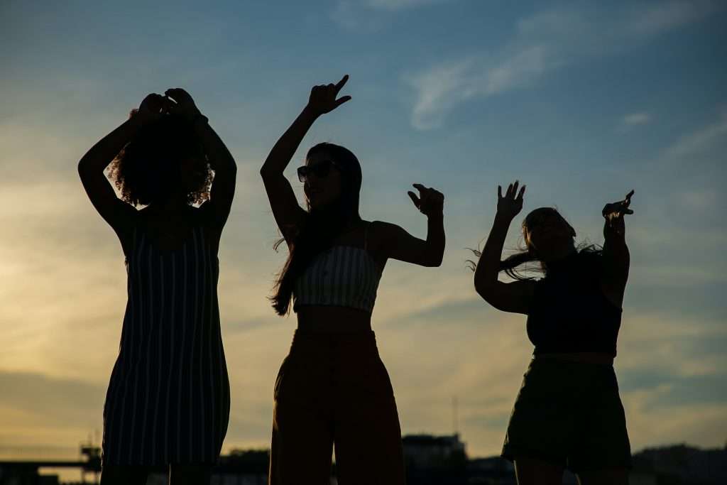 tres chicas bailando en el atardecer